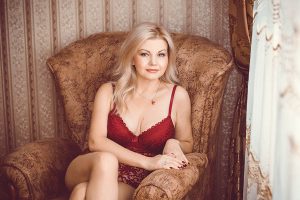 Kalinka im roten Dessous auf Sessel bereit für Telefonsex