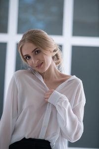Sofie lächelt verführerisch beim Telefonsex in transparenter Bluse